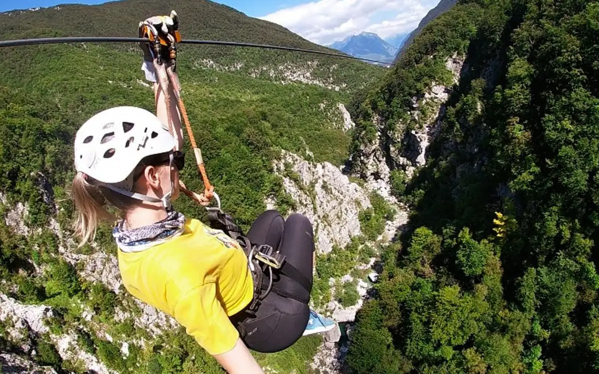 A rider on a zipline cable above the deep rocky Učja canyon at Bovec