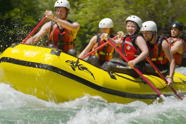 A yellow raft of six punching through white water on the Sava