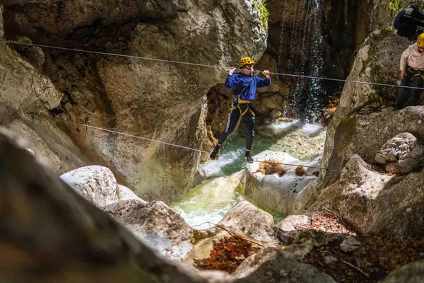 A climber on a wire crossing a gorge beside a waterfall